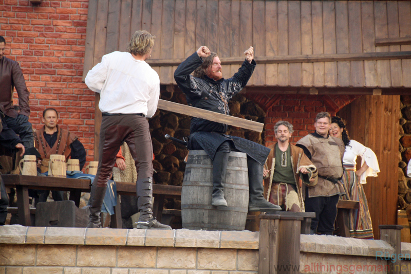 Tonnen klatschen - Klaus Störtebeker (Alexander Koll) attempts to knock Goedeke Michels (Alexander Hanfland) off the barrel