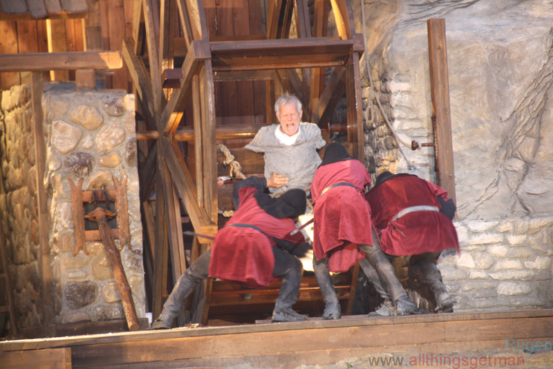 Armin von Alkun (Norbert Braun) being tied to the Water Wheel