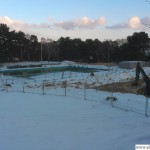 The outdoor pool is partially frozen and covered in snow