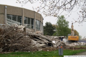 A digger clears part of the debris from the old indoor swimming pool building