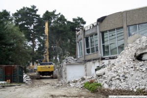 A digger drives past one of the part-demolished walls