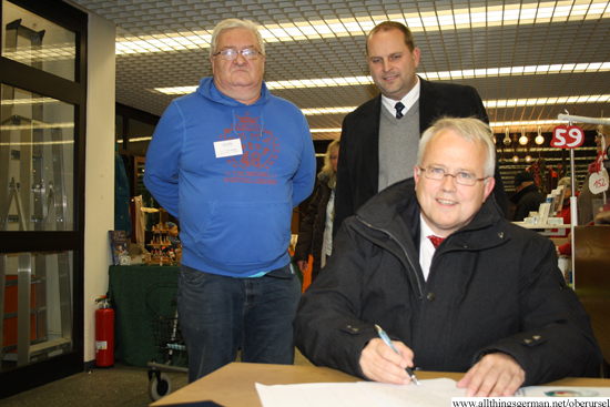 Mayor Hans-Georg Brum signing the petition to allow the Yang family to stay in Germany.  In the background are Dr.Franz Zenker from the Ausländerbeirat (left) and the town's treasurer Thorsten Schorr.