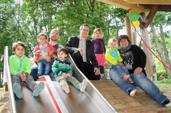Alderman Christof Fink (centre) on the re-vamped slided with one of the fathers Alireza Dorfard (left), daycare worker Marion Meuer (right) and some of the children at the official opening
