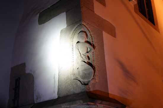 A figure on the side of the St. Ursula Church with the Eppstein coat of arms during a full moon